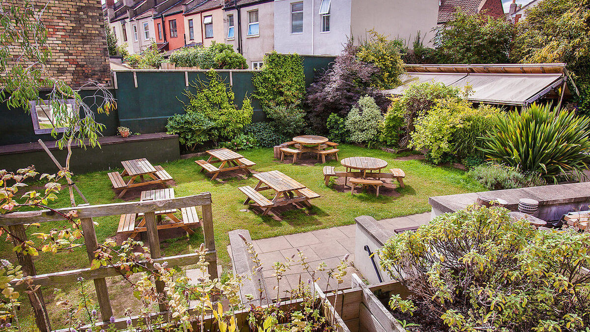 Vibrant beer garden at The Spotted Cow with wooden tables, murals, and twinkling fairy lights