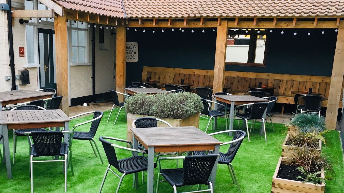Courtyard garden at The Shakespeare with tables, umbrellas, and fairy lights on a warm afternoon